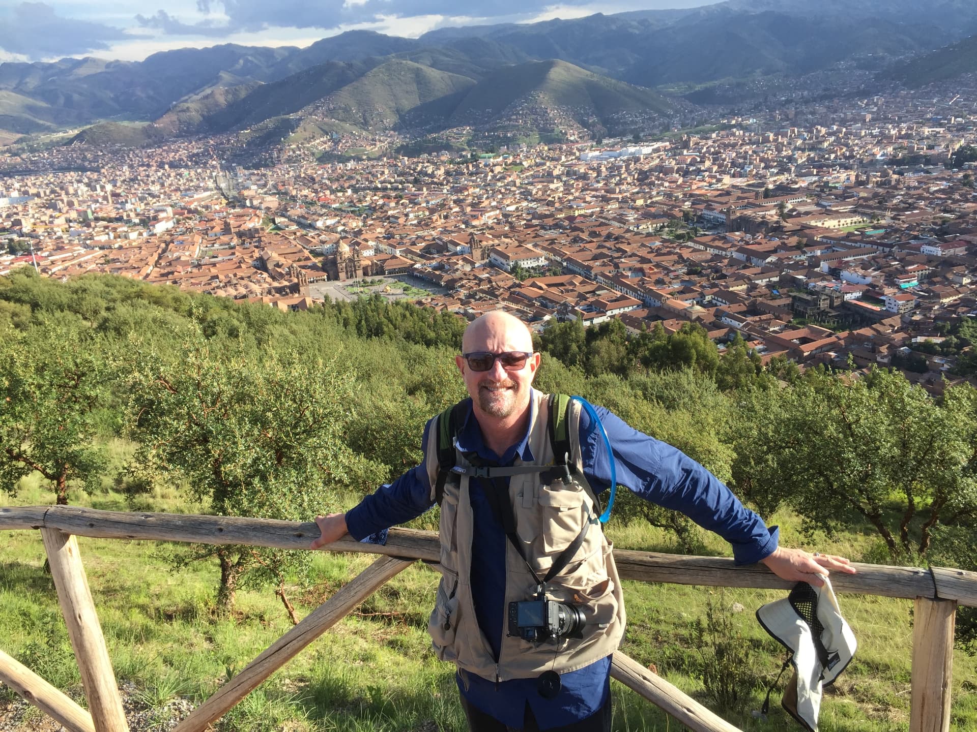 The photographer behind Photos by LJH, with a camera around his neck overlooking a city and mountains.